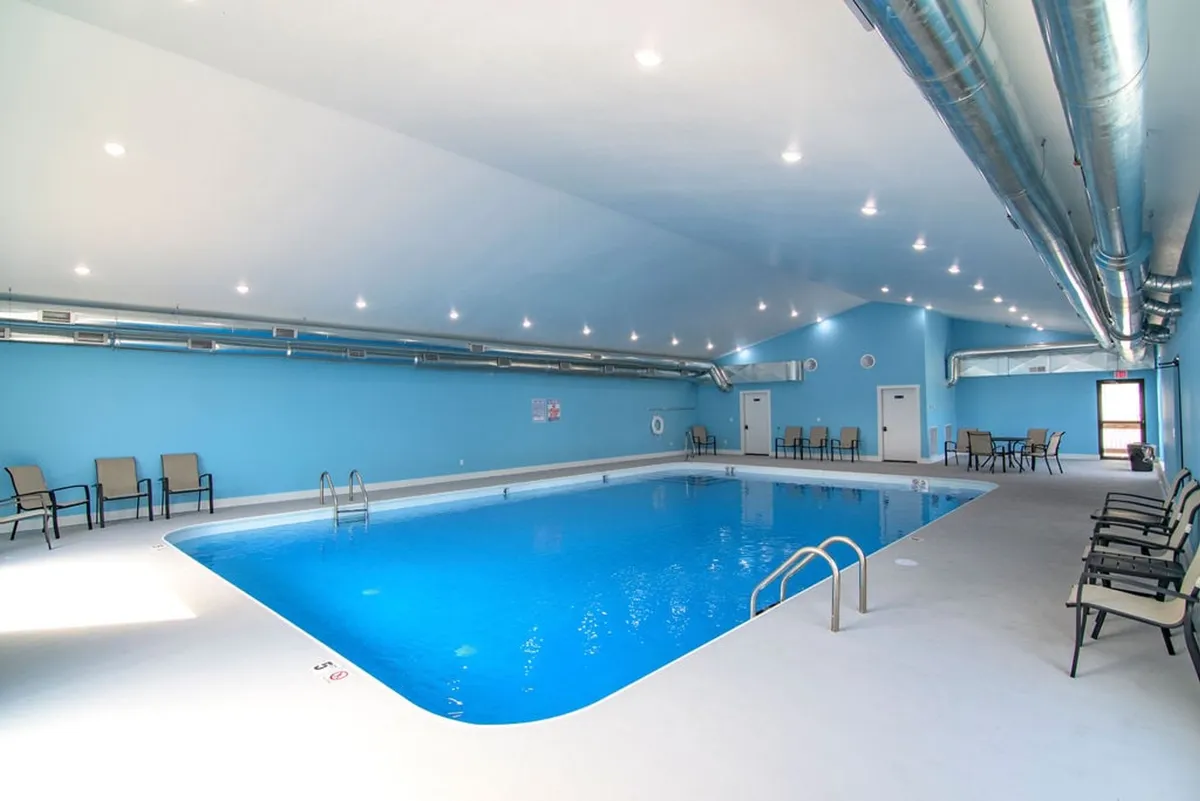 This interior view shows a spacious, accessible indoor swimming pool with blue walls and comfortable seating, just a short step-free walk from the main living areas.