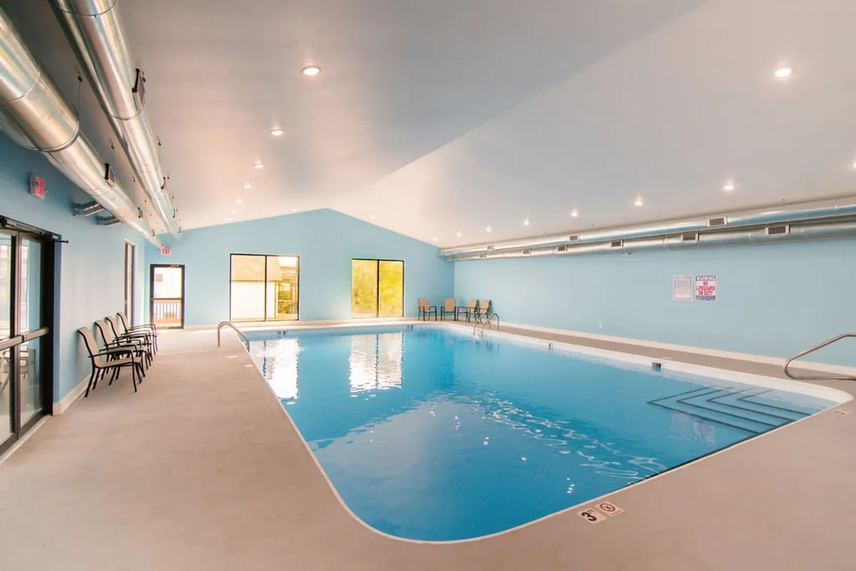 An inviting indoor swimming pool with large windows that fill the space with natural light. Comfortable seating lines the pool area, creating a tranquil spot for swimming and relaxation regardless of the weather.